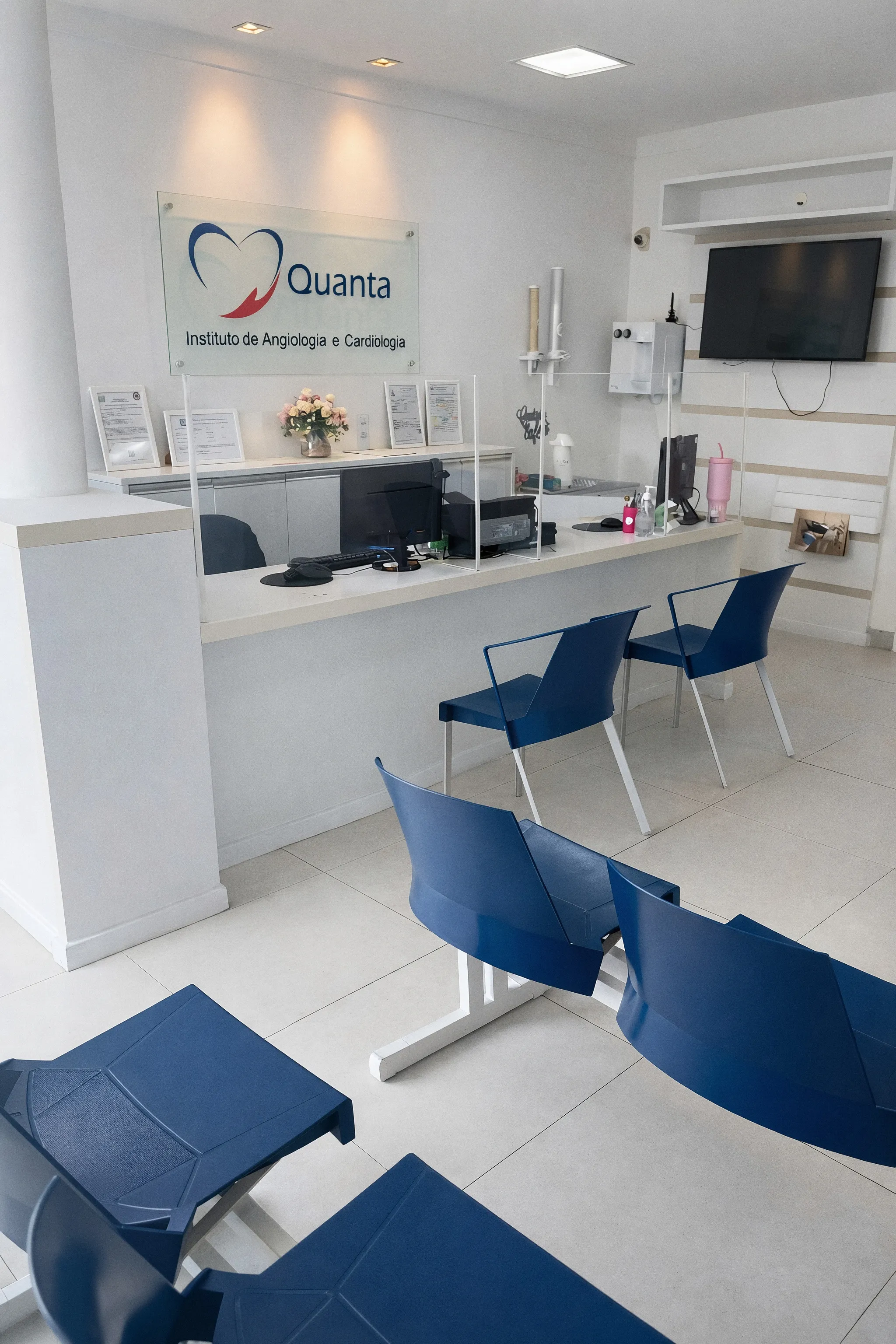 Recepção da Quanta Saúde com cadeiras azuis e balcão de atendimento